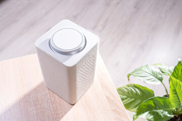 electronic equipment smart speaker on the table in the room and houseplant,  smart speaker. gadget in the apartment close-up, selective focus, tinted image, bright sunlight from the window
