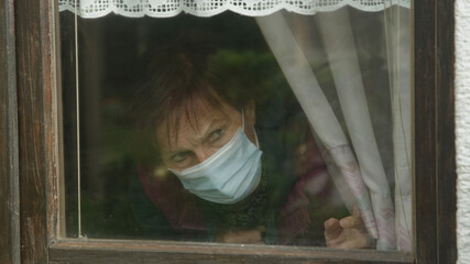 CLOSE UP: Lonely lady anxiously observes neighborhood in the midst of pandemic.