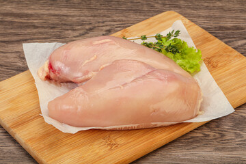 Raw chicken breast over board