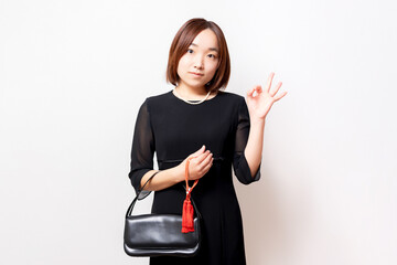 喪服を着てOKのジェスチャーをする女性