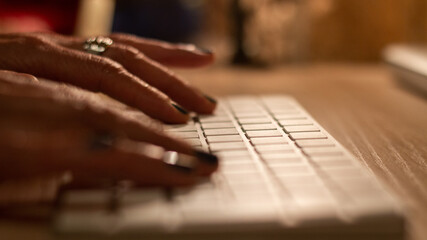 Persona haciendo teletrabajo desde casa. En la foto aparecen unas manos tecleando encima de una mesa de madera. 