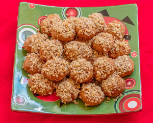 melomacarona, traditional Greek Christmas gourmet cookies with honey syrup and nuts, served on red fabric background