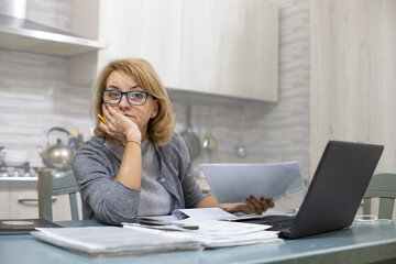 Mature woman suffering from vitiligo is working on computer from home. Working at a distance, away from the office. With earphones she listens to music for relaxation