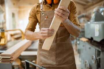 Carpenter folds wooden bars together at the workshop, close-up on hands