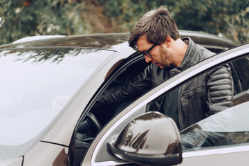 Stylish man in glasses sits in a car