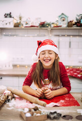 Blurred focus of a teenage girl standing in the kitchen sculpting dough for gingerbread cookies.