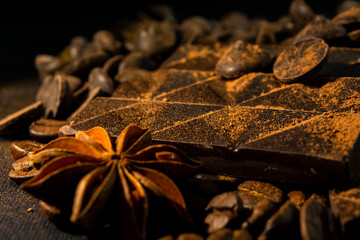 background of broken chocolate and raw materials, star anise, cocoa, cinnamon