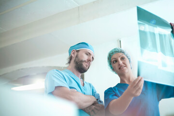 Male and female doctors discussing over medical x-ray image in hospital