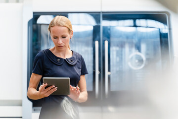 Blond businesswoman using digital tablet while standing in factory