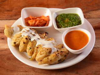 Chicken malai momo with sauce and mint chutney served over a rustic wooden background, selective focus