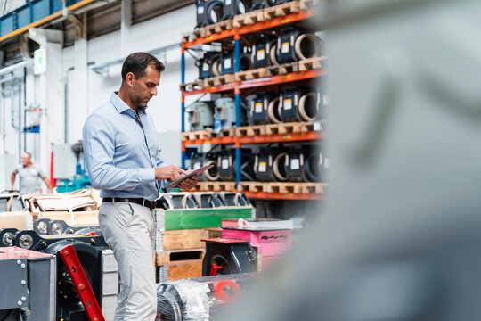 Male entrepreneur concentrating while using digital tablet standing at industry