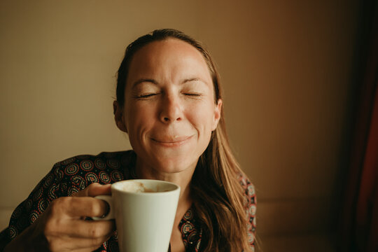 Female entrepreneur drinking coffee while sitting in office against wall