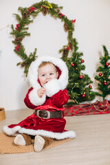 Little cute boy dressed as Santa near little Christmas trees. Christmas mood