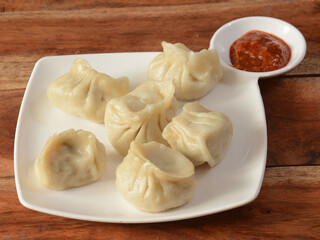Chicken steam momo. Nepalese Traditional dish Momo stuffed with chicken and then cooked and served with sauce over a rustic wooden background, selective focus