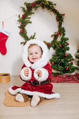 Little cute boy dressed as Santa near little Christmas trees. Christmas mood