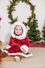 Little cute boy dressed as Santa near little Christmas trees. Christmas mood