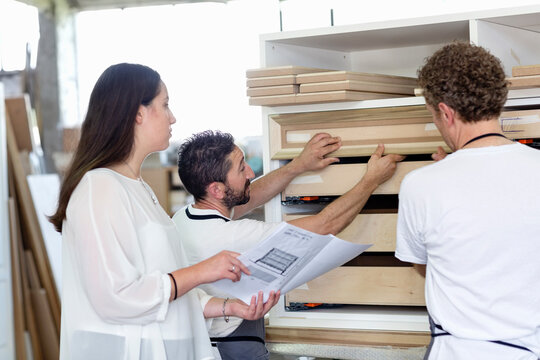 Interior designer and expertise fitting frames in drawer while standing at workshop