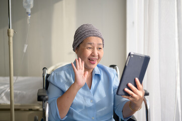 Cancer patient woman wearing head scarf making video call on social network with family and friends...