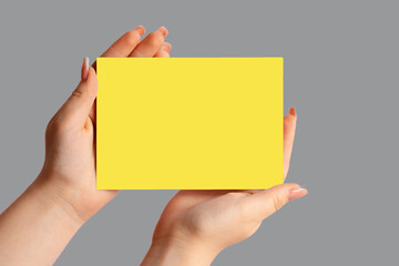 Woman hand showing Yellow business card on Ultimate Gray background