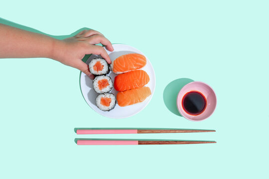 Hand of little girl picking up piece of maki sushi