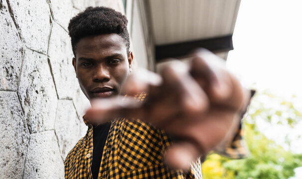 Young man stretching hand while standing by wall