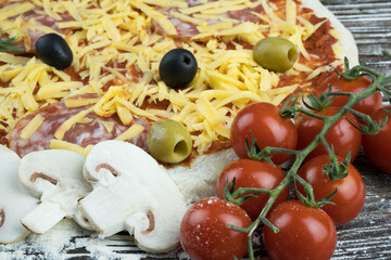Pizza preparation. Raw dough with grated cheese and ingredients