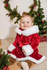 Little cute boy dressed as Santa near little Christmas trees. Christmas mood