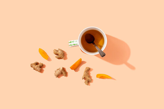 Studio shot of mug of herbal tea, ginger roots and peach slices