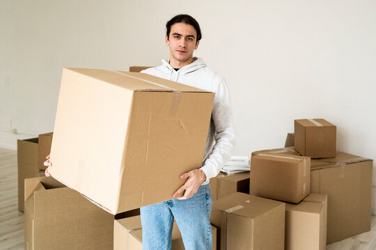 Young man carrying cardboard box in new house
