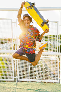 Cheerful man with skateboard jumping on bridge
