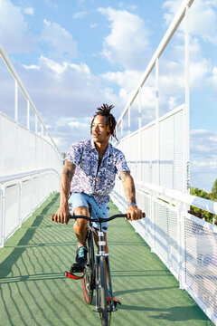 Man listening music while riding bicycle on bridge