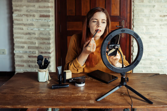 Beautician applying make up while filming tutorial at home