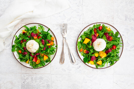 Two plates of vegetarian salad with fruits, vegetables and burrata cheese