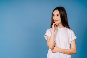 Attractive excited young girl wearing casual clothing standing isolated over blue background looking away on empty space for your text