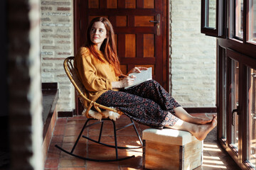 Beautiful woman looking away while writing in book at home