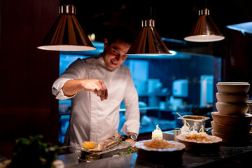 Male chef sprinkling seasoning seafood in kitchen at restaurant