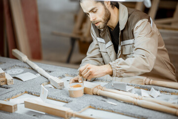 Manual worker finishing wooden products, spackling and grinding baluster at the carpentry manufacturing