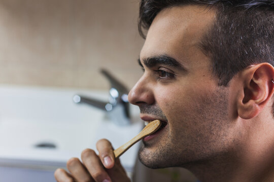 Young man brushing teeth with bamboo toothbrush
