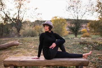 Fototapeta premium Woman practicing yoga and stretching on the park bench