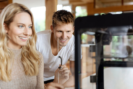 Business people looking at 3D printer while sitting at home