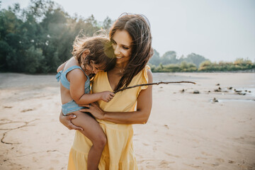Happy mother holding daughter in arms at beach