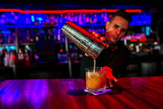 Mid adult man mixing cocktail drink while standing in bar