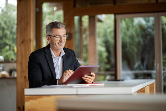 Smiling businessman using digital tablet while sitting at home