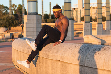 Sportsman doing abdominal muscle exercise while sitting on retaining wall at park