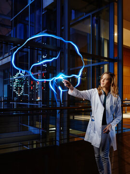Female doctor light painting brain at laboratory in hospital