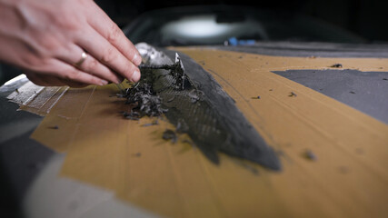 A close-up of a man's hand with a tool. A professional removes the form from the clay with the help of a cycle. The production