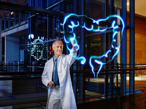 Smiling male gastroenterologist examining large intestine with light painting at hospital