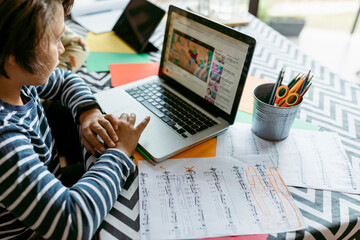 Boy watching online video on laptop while sitting at table