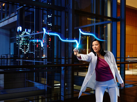 Mature female cardiologist light painting heart attack pulse in laboratory at hospital