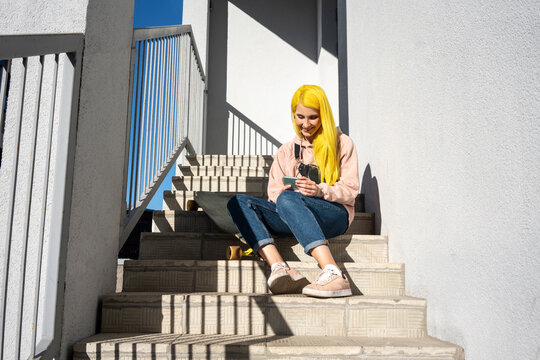 Young woman using smart phone while sitting on steps